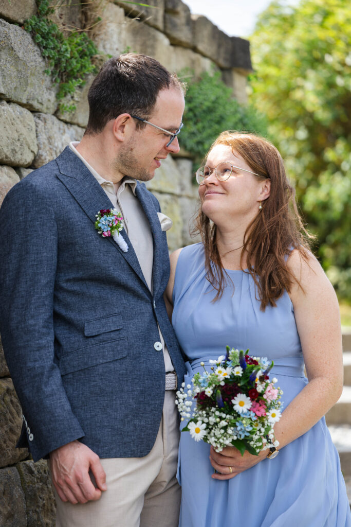 Hochzeitsfotografie aus Stuttgart – Linda & Ilyas lächeln sich vor einer Natursteinmauer an